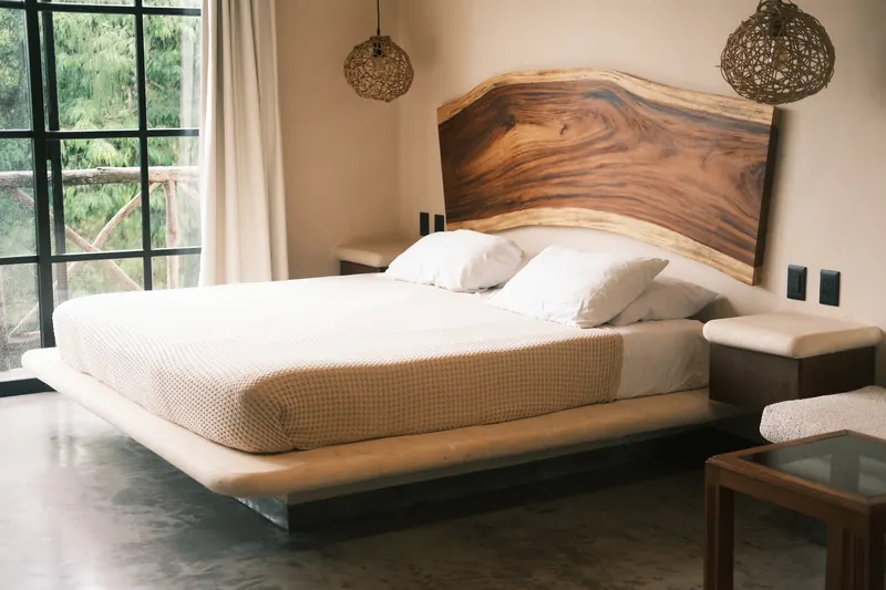 Une chambre d’hôtel : lit blanc et tête de lit en bois massif.