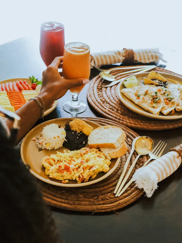 Une table de petit-déjeuner vue de dessus : œufs brouillés, fruits et jus.